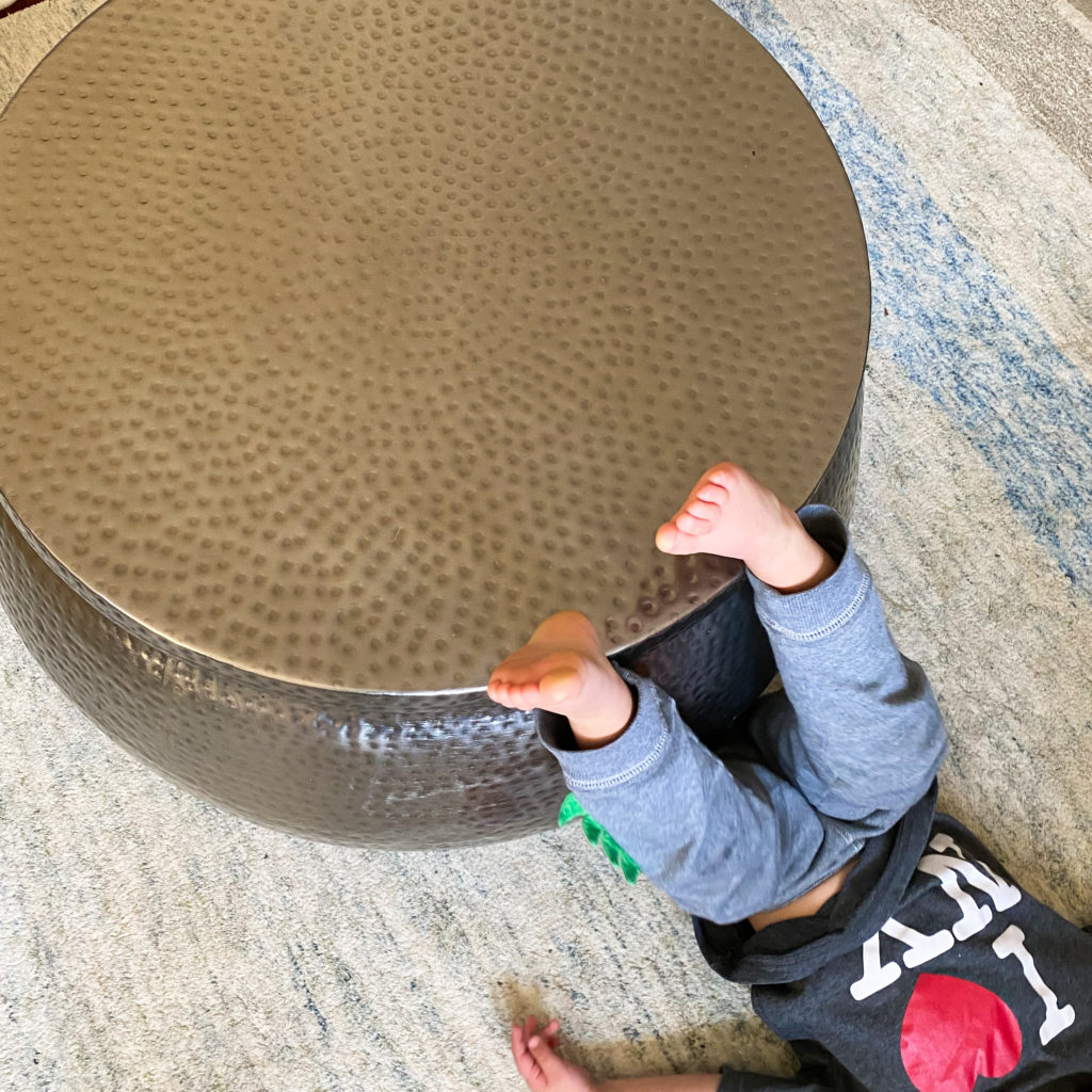 Round metal coffee table with storage and child leaning on it